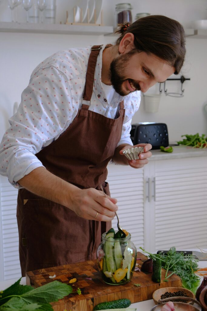 Man preparing a meal including fermented pickles that he is taking from a glass jar.